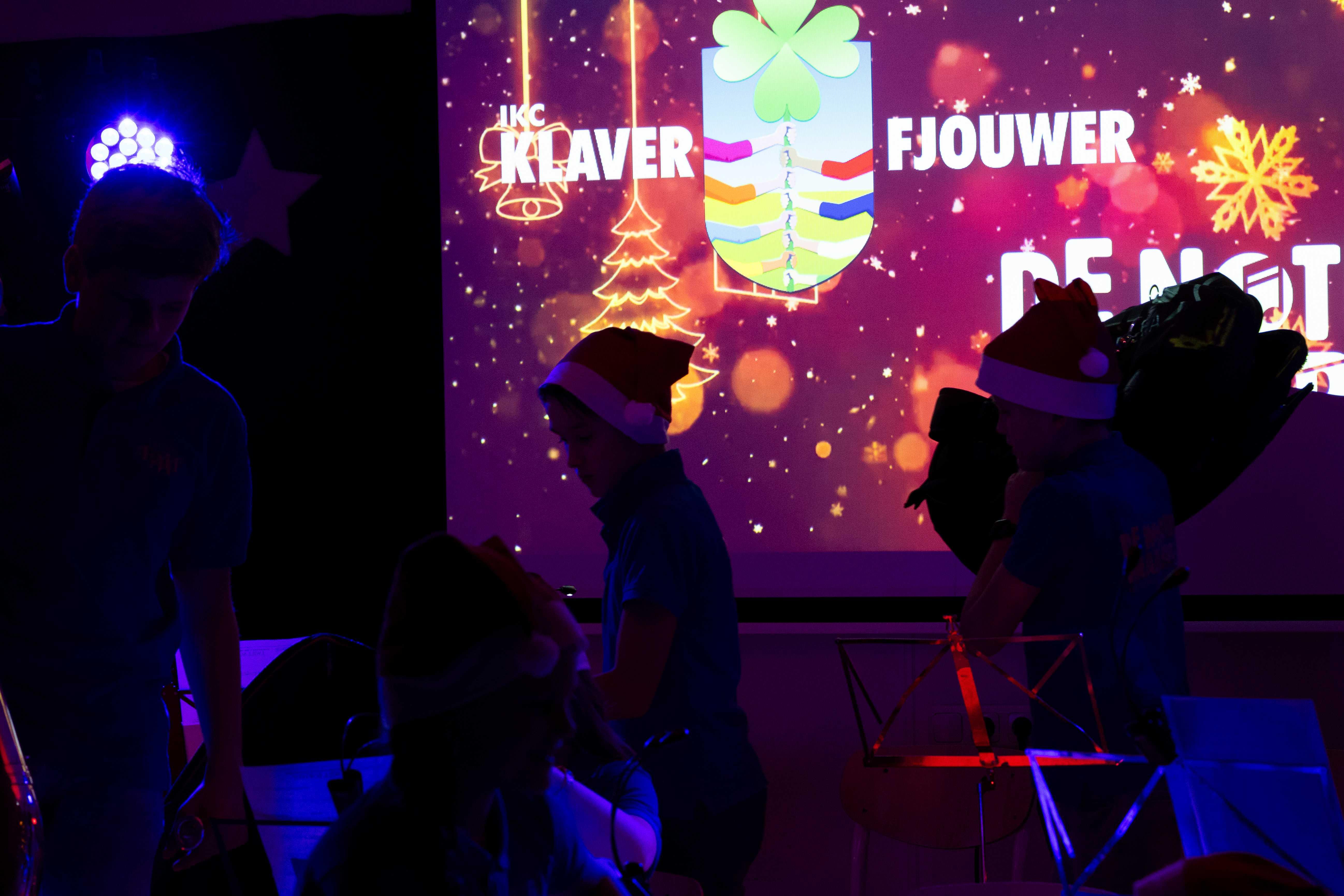 Afbeelding van een evenement bij IKC Klaver Fjouwer in Oudega (Gem. Súdwest-Fryslân) met leerlingen in kerstcaps en een kleurrijke achtergrond. Afbeelding van een evenement bij IKC Klaver Fjouwer in Oudega (Gem. Súdwest-Fryslân) met leerlingen in kerstcaps en een kleurrijke achtergrond.