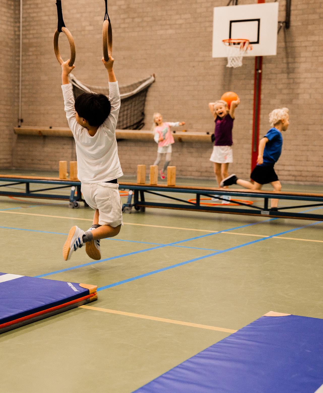 Afbeelding van kinderen die actief sporten in de gymzaal van de Paasbergschool in Ede.