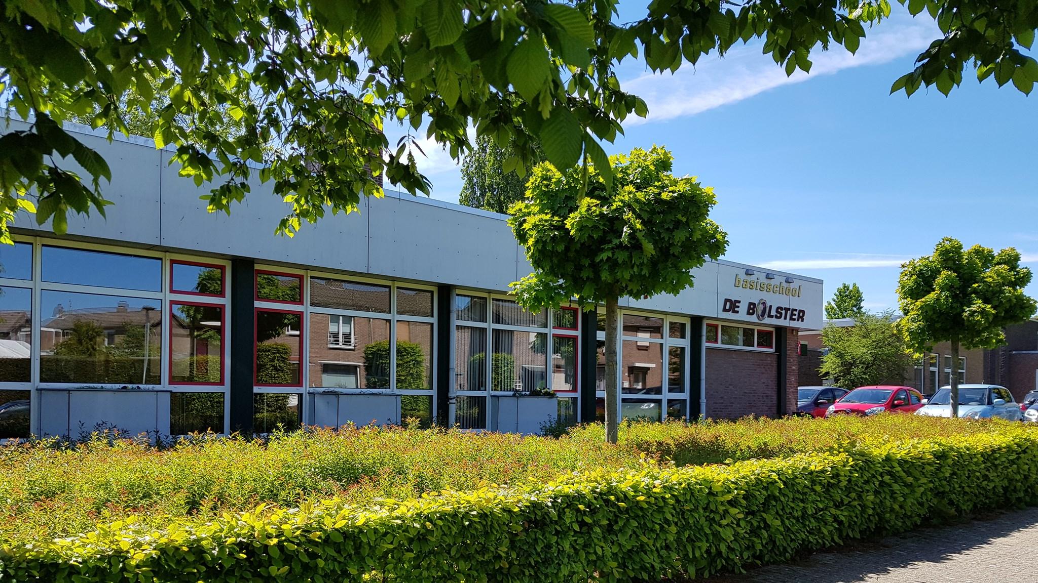 Basisschool De Bolster in Nuth, omringd door groene struiken en bomen. Basisschool De Bolster in Nuth, omringd door groene struiken en bomen.