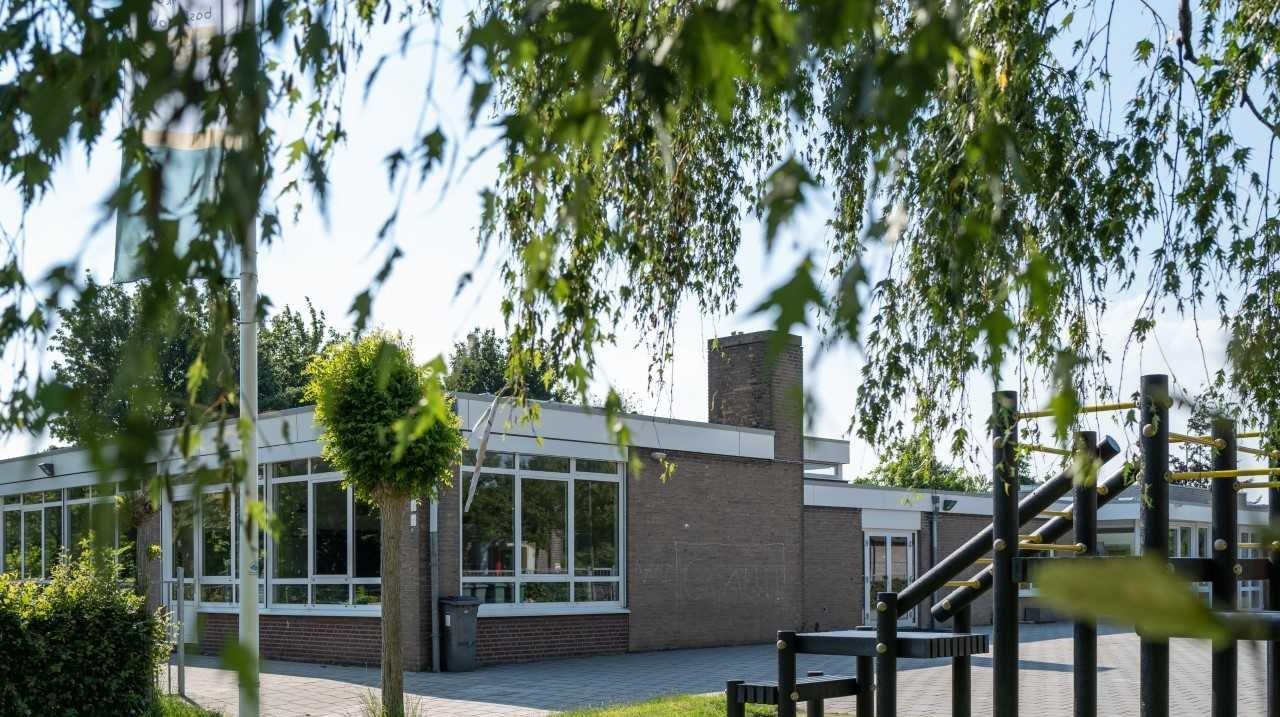 Basisschool de Den in Mheer met een duidelijk zicht op het schoolplein en de speeltoestellen.