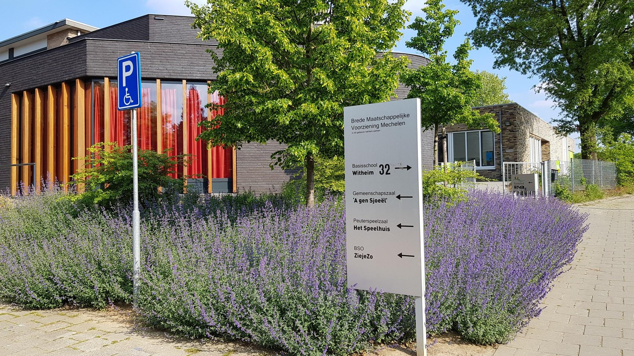 Basisschool Witheim in Mechelen met bloeiende struiken en een parkeersymbool. Basisschool Witheim in Mechelen met bloeiende struiken en een parkeersymbool.