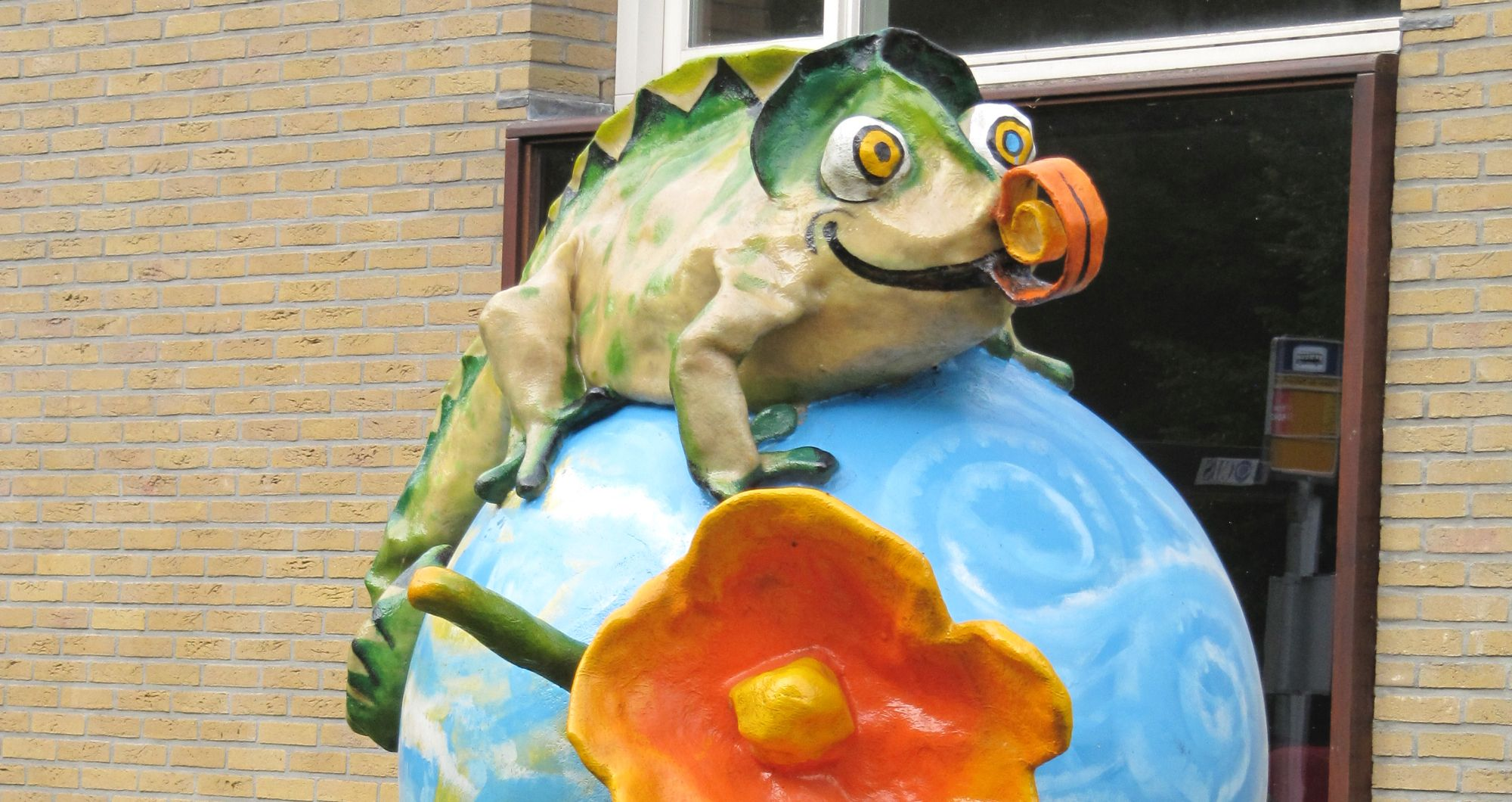 Beeld van een kleurrijk kameleonbeeld dat de buitenkant van WereldKidz Kameleon in Doorn siert. Beeld van een kleurrijk kameleonbeeld dat de buitenkant van WereldKidz Kameleon in Doorn siert.