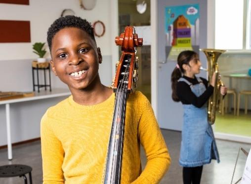 Blij kind met een contrabas in klaslokaal van Basisschool De Botteloef in Amsterdam. Blij kind met een contrabas in klaslokaal van Basisschool De Botteloef in Amsterdam.