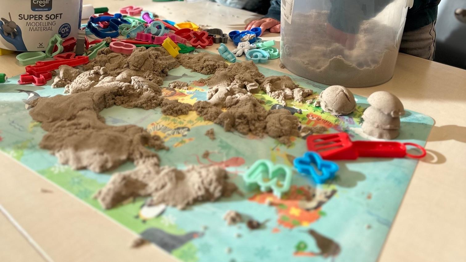 De afbeelding toont een creatieve activiteit met modelleerklei en vormen op de tafel van Basisschool Aventurijn in Houten. De afbeelding toont een creatieve activiteit met modelleerklei en vormen op de tafel van Basisschool Aventurijn in Houten.