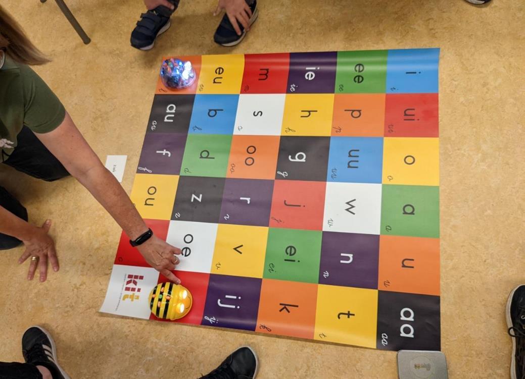 De afbeelding toont een educatieve activiteit met een kleurenmat en een robotica-tool op de A Willeboerschool in Rotterdam. De afbeelding toont een educatieve activiteit met een kleurenmat en een robotica-tool op de A Willeboerschool in Rotterdam.