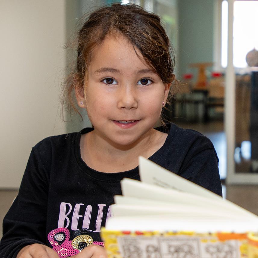 De afbeelding toont een glimlachend meisje dat een boek leest in De Wereldwijzer, Alphen aan den Rijn. De afbeelding toont een glimlachend meisje dat een boek leest in De Wereldwijzer, Alphen aan den Rijn.