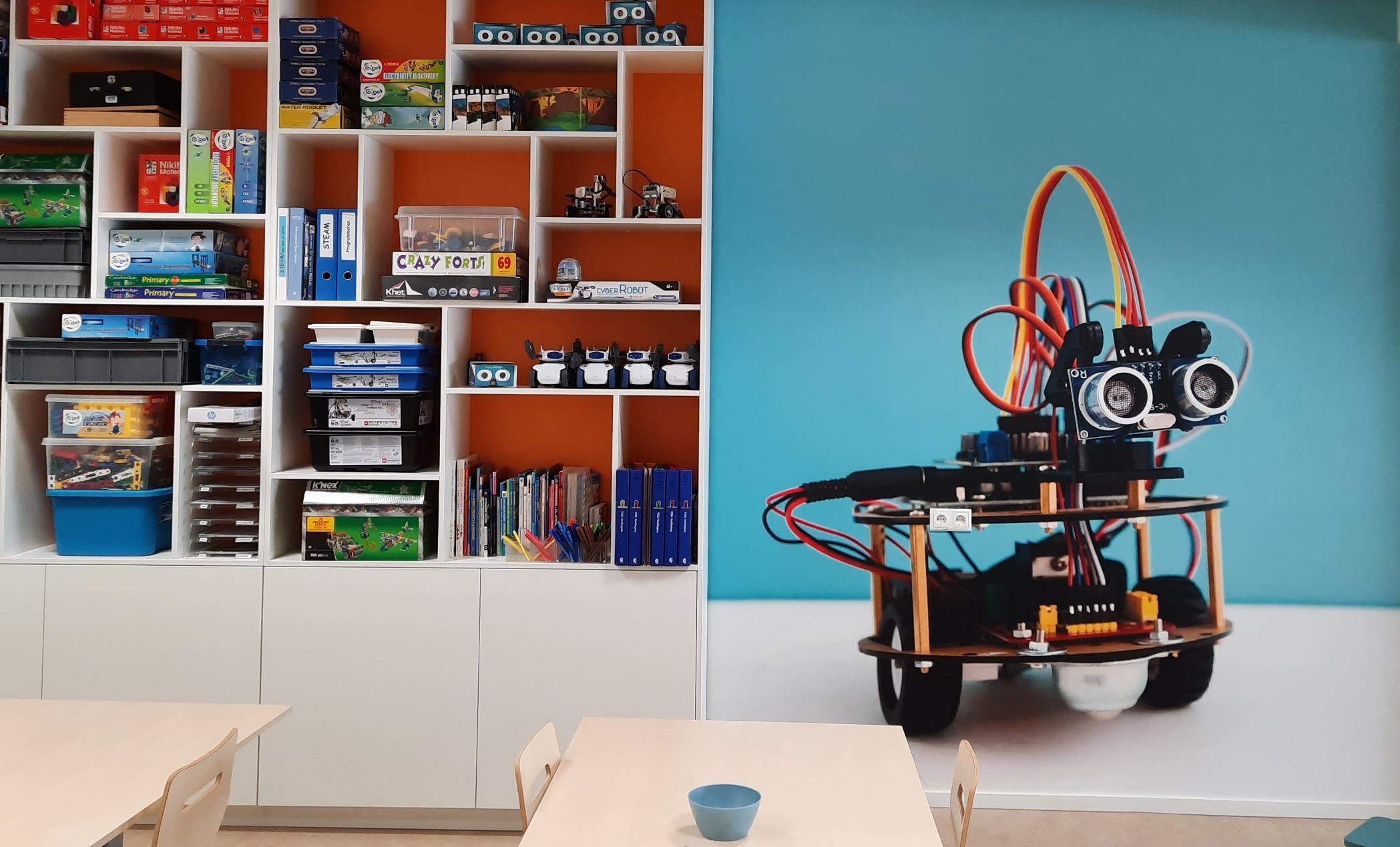 De afbeelding toont een leeromgeving met technische leermaterialen en een robot aan de muur van Openbare Basisschool Futura in Scheemda.