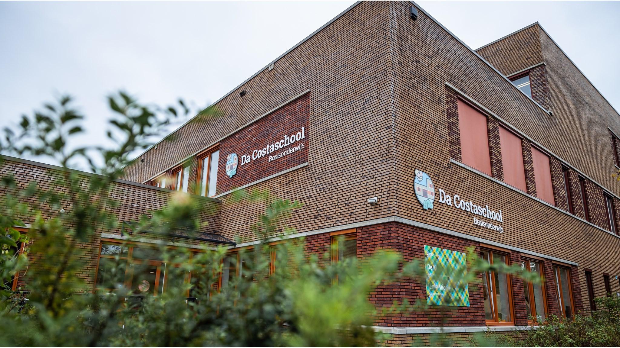 De buitenkant van de Da Costaschool in Hilversum, zichtbaar omringd door groen. De buitenkant van de Da Costaschool in Hilversum, zichtbaar omringd door groen.