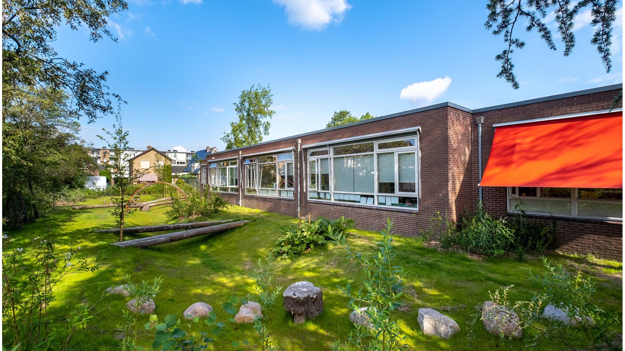 De buitenkant van de PC Daltonschool Willem van Oranje in Apeldoorn met een groen schoolplein en moderne ramen. De buitenkant van de PC Daltonschool Willem van Oranje in Apeldoorn met een groen schoolplein en moderne ramen.