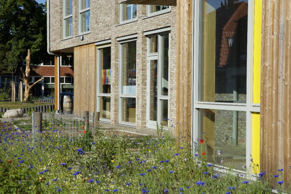 De gevel van Sterrenschool Hilversum met kleurrijke bloemen en grote ramen. De gevel van Sterrenschool Hilversum met kleurrijke bloemen en grote ramen.