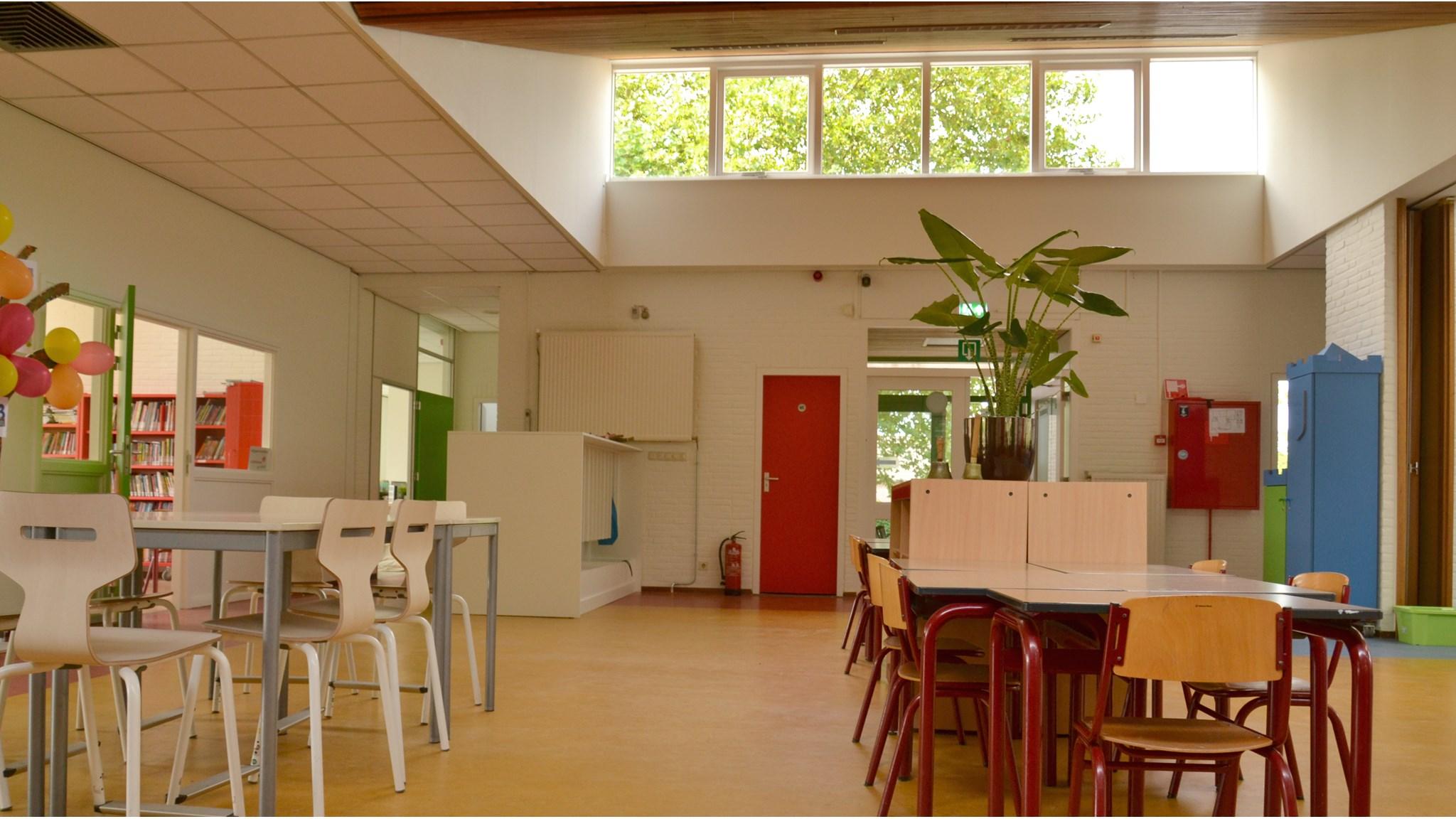 De lichte en ruime binnenruimte van Basisschool De Zeveneik in Bingelrade, met moderne tafels en stoelen. De lichte en ruime binnenruimte van Basisschool De Zeveneik in Bingelrade, met moderne tafels en stoelen.