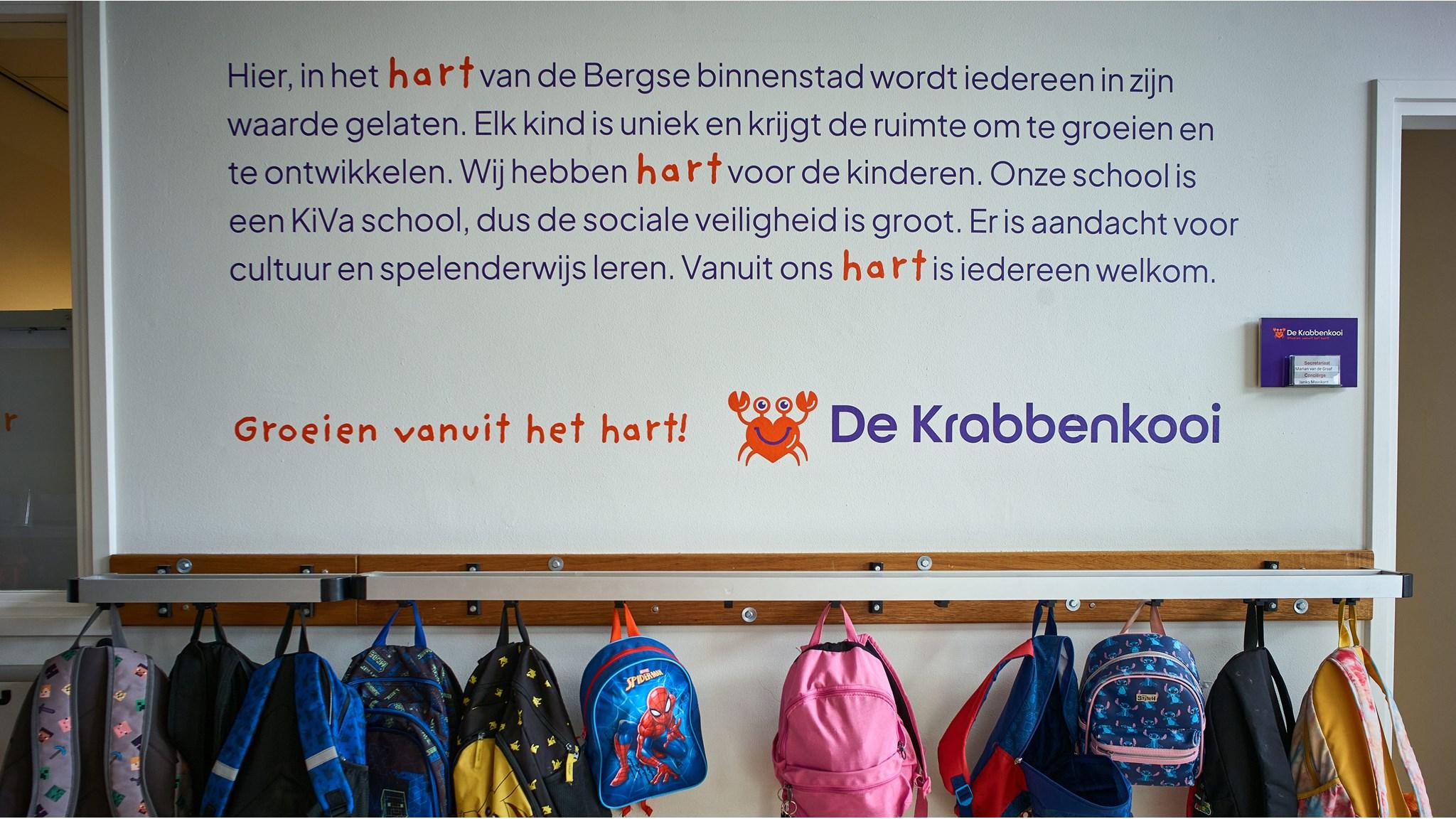 De muur van Basisschool De Krabbenkooi in Bergen op Zoom benadrukt groei en ontwikkeling met de boodschap "Groeien vanuit het hart!" en kleurrijke rugzakken. De muur van Basisschool De Krabbenkooi in Bergen op Zoom benadrukt groei en ontwikkeling met de boodschap "Groeien vanuit het hart!" en kleurrijke rugzakken.
