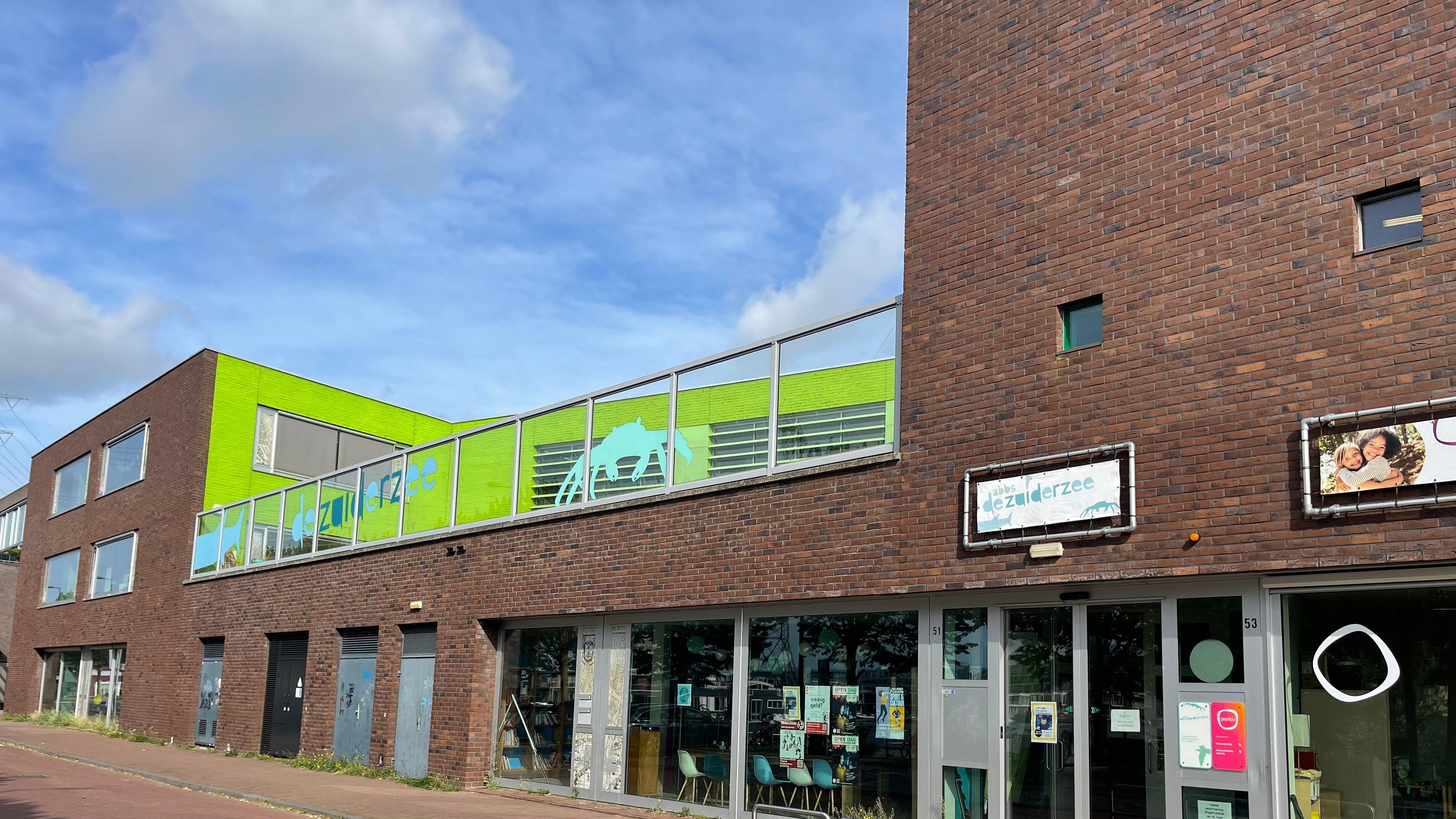 De school De Zuiderzee in Amsterdam met een levendige groene gevel en moderne architectuur. De school De Zuiderzee in Amsterdam met een levendige groene gevel en moderne architectuur.