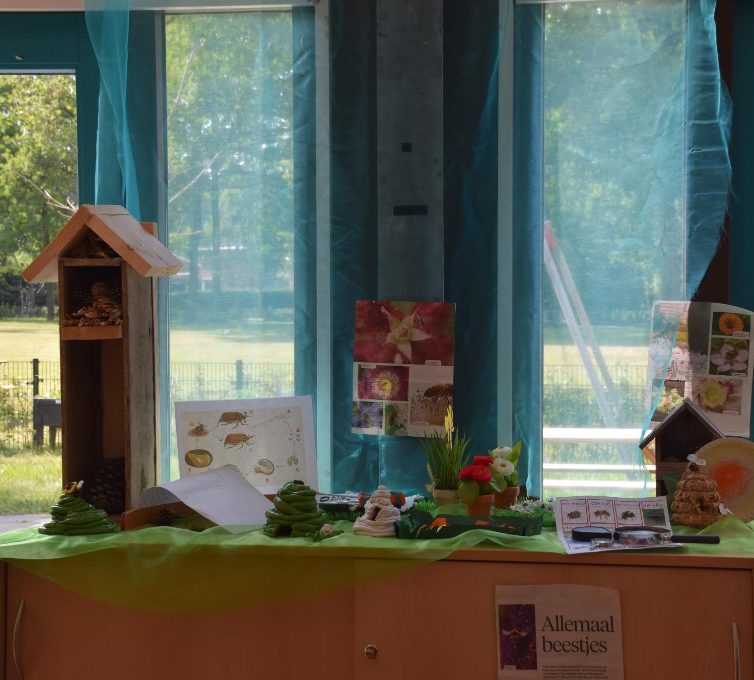 Deze afbeelding toont een creatief project in de klas van De Meander in Losser, met kunstwerken en materialen die de natuur en insecten onderwerpen.