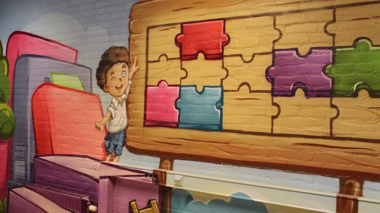 Deze afbeelding toont een kleurrijke muurschildering in Basisschool 't Breerke' in Maasbracht met een jongen die puzzelstukken speelt. Deze afbeelding toont een kleurrijke muurschildering in Basisschool 't Breerke' in Maasbracht met een jongen die puzzelstukken speelt.