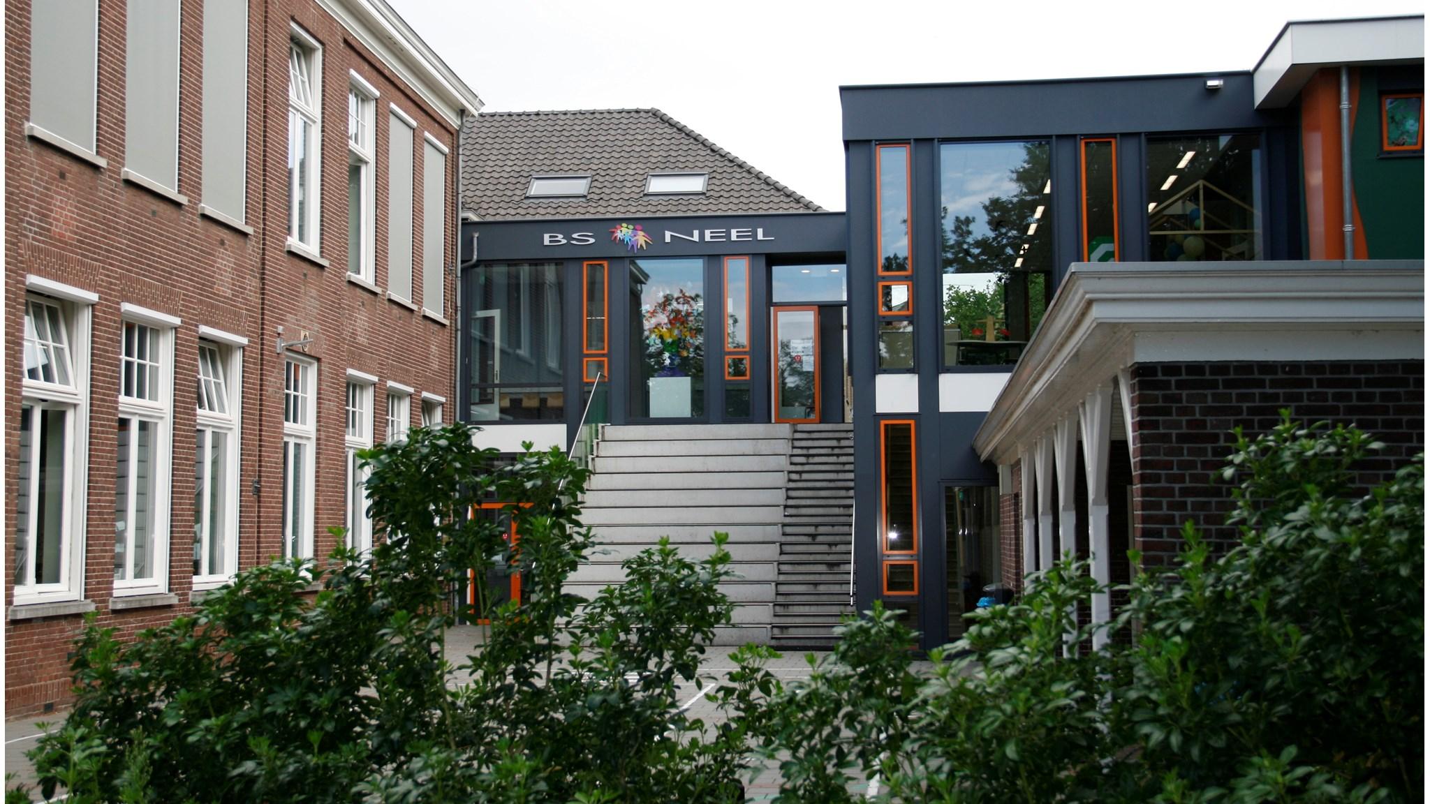 Dit is de ingang van Basisschool Neel in Roermond, omringd door groene planten en een moderne gevel. Dit is de ingang van Basisschool Neel in Roermond, omringd door groene planten en een moderne gevel.