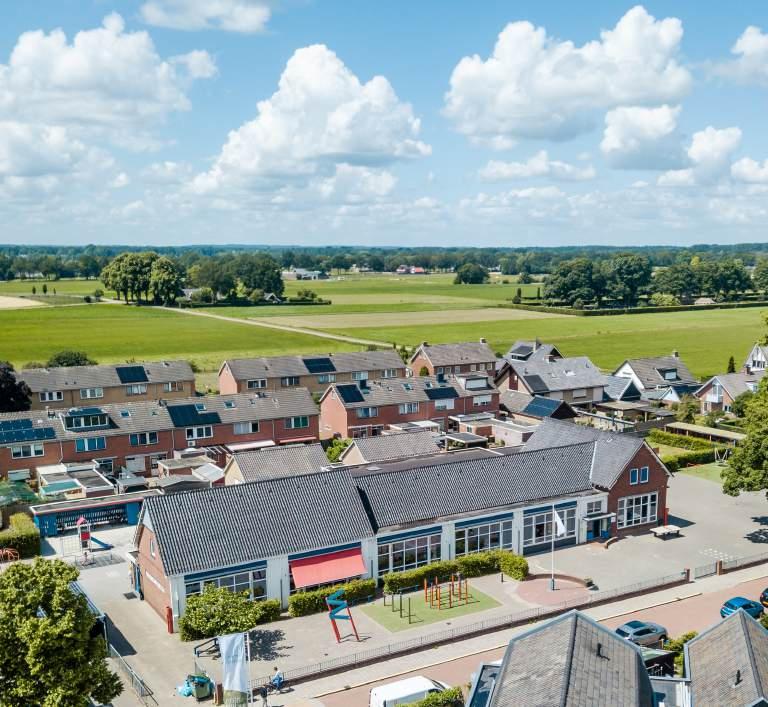 Dit is een luchtfoto van de school De Wegwijzer in Enter, met een overzicht van het schoolplein en de omliggende woningen. Dit is een luchtfoto van de school De Wegwijzer in Enter, met een overzicht van het schoolplein en de omliggende woningen.