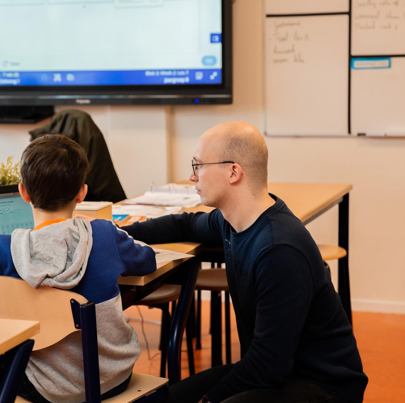 Docent en leerling werken samen aan een laptop in de klas van de Paasbergschool in Ede.