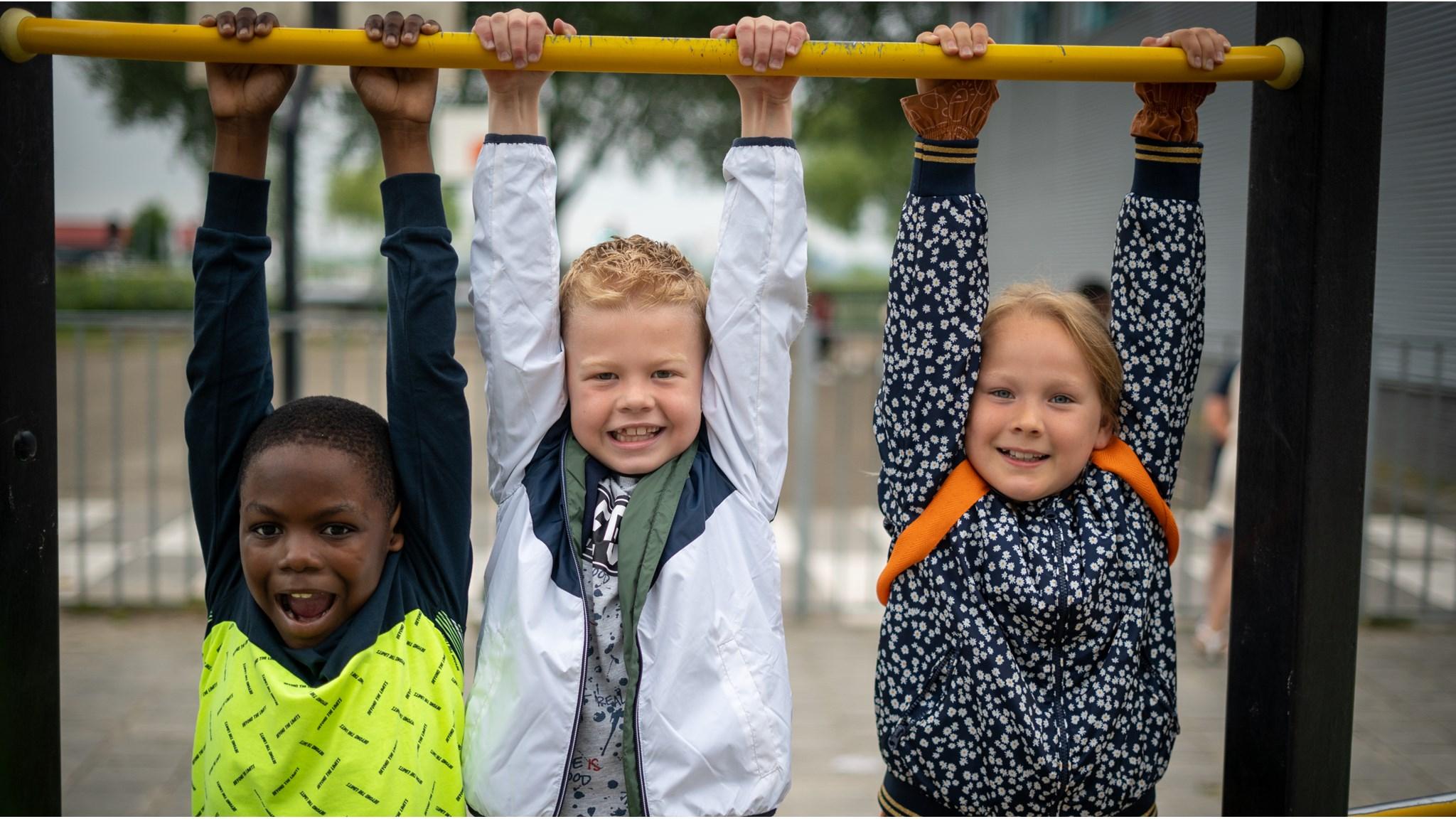 Drie blije kinderen hangen aan de playgroude bij Oecumenische Daltonschool De Windwijzer in Almere. Drie blije kinderen hangen aan de playgroude bij Oecumenische Daltonschool De Windwijzer in Almere.