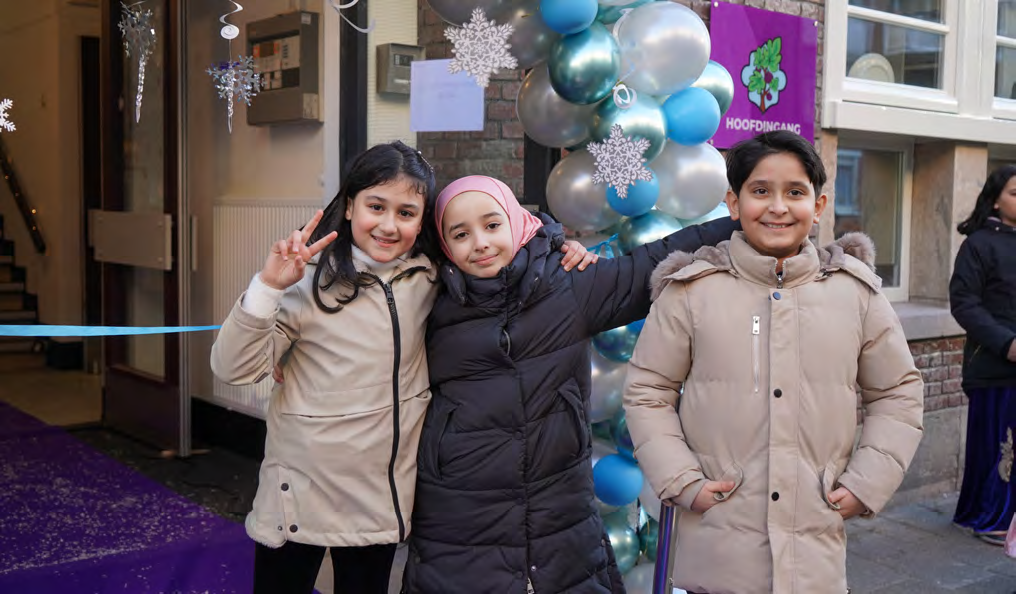 Drie blije kinderen poseren voor de ingang van IBS De Vijgenboom in Amsterdam. Drie blije kinderen poseren voor de ingang van IBS De Vijgenboom in Amsterdam.