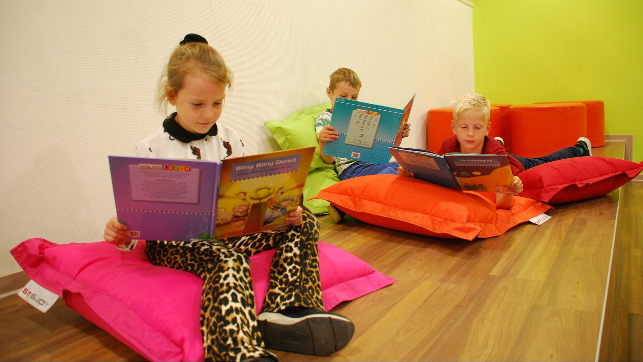 Drie kinderen lezen boeken op kleurrijke kussens in obs De Dubbelburg in Valkenburg (Zuid-Holland). Drie kinderen lezen boeken op kleurrijke kussens in obs De Dubbelburg in Valkenburg (Zuid-Holland).