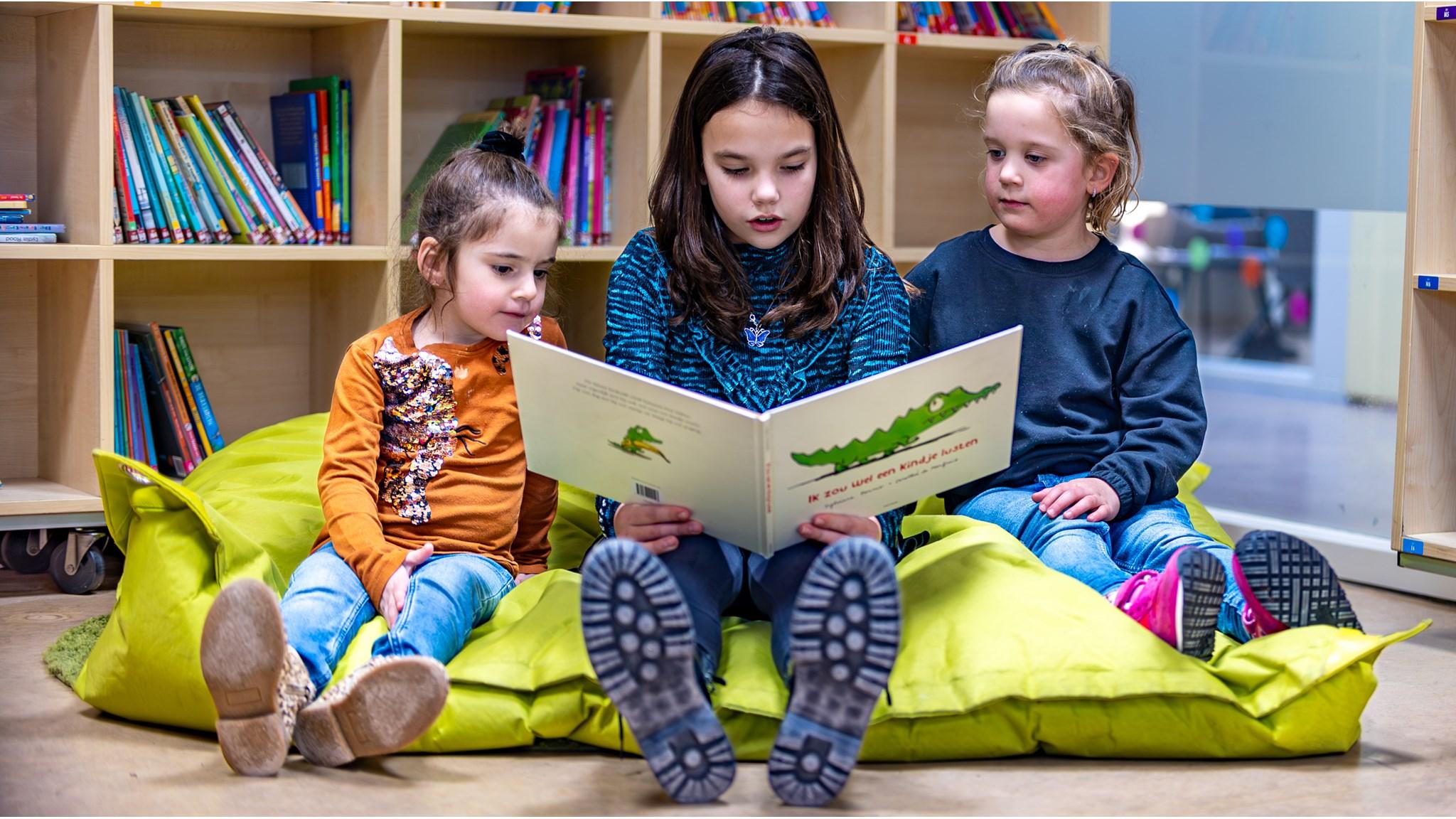 Drie kinderen lezen samen een boek op kussens in de bibliotheek van Basisschool 't Maxend in Nistelrode. Drie kinderen lezen samen een boek op kussens in de bibliotheek van Basisschool 't Maxend in Nistelrode.
