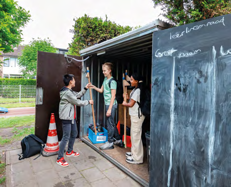 Drie leerlingen van IKC de Driemaster uit Hoek van Holland praten bij een opslagruimte op het schoolplein. Drie leerlingen van IKC de Driemaster uit Hoek van Holland praten bij een opslagruimte op het schoolplein.