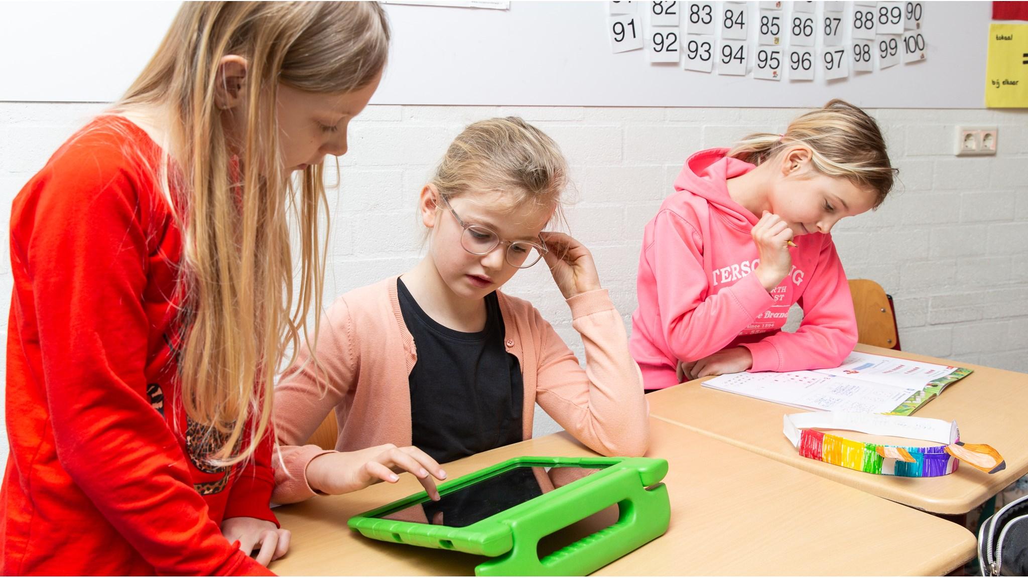 Drie leerlingen van IKC Wynwizer in Leeuwarden werken samen aan een tablet in de klas. Drie leerlingen van IKC Wynwizer in Leeuwarden werken samen aan een tablet in de klas.
