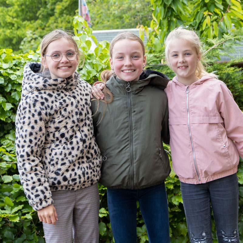 Drie vrolijke leerlingen van Palmenhof in Middelburg poseren samen voor een groene achtergrond. Drie vrolijke leerlingen van Palmenhof in Middelburg poseren samen voor een groene achtergrond.
