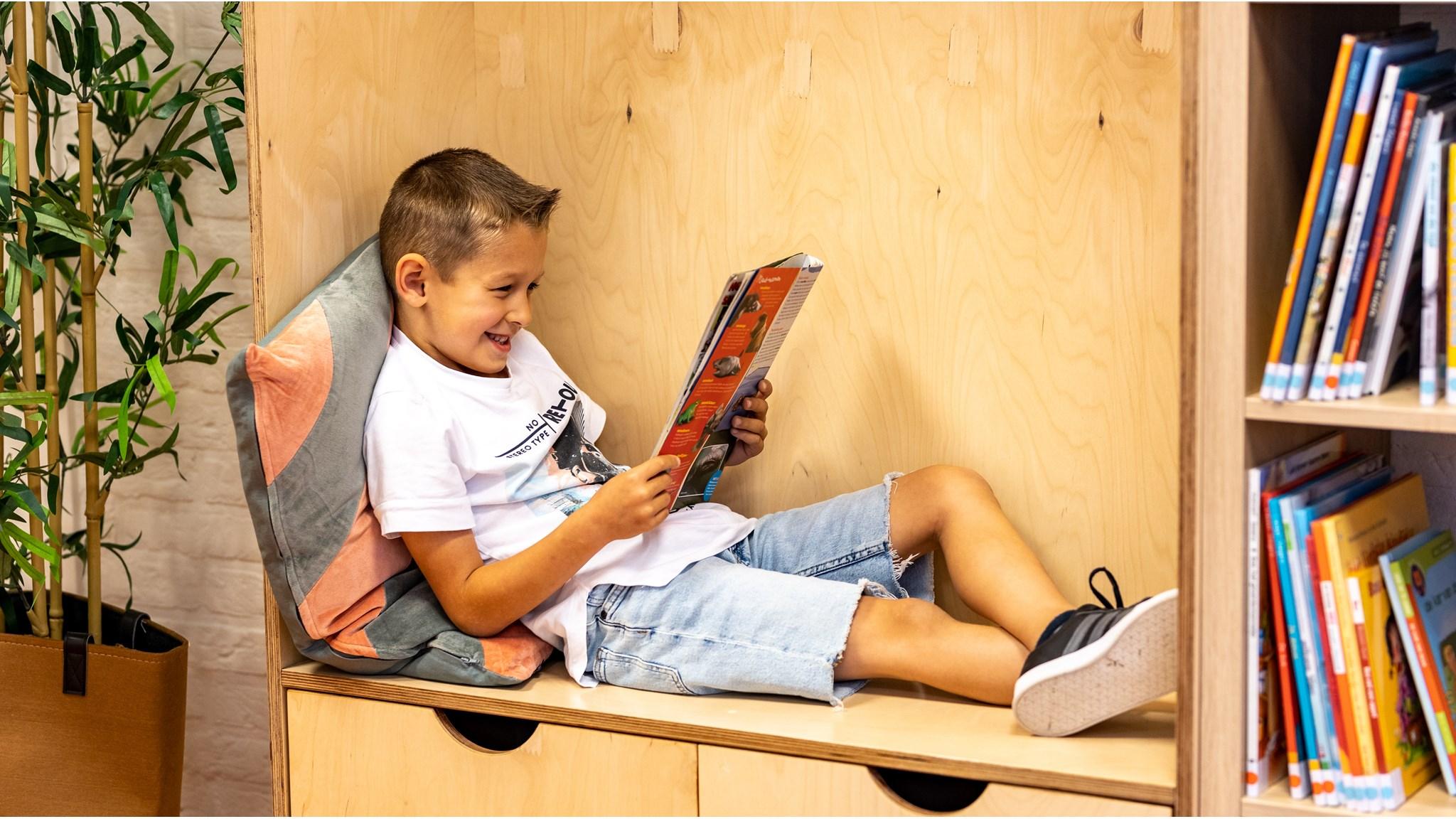 Een blije jongen leest een boek in de leeshoek van Basisschool De Cirkel in Gouda. Een blije jongen leest een boek in de leeshoek van Basisschool De Cirkel in Gouda.