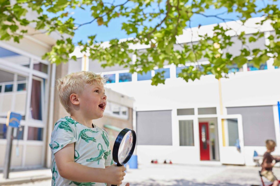 Een blije jongen met een vergrootglas op het schoolplein van de Zwetteschool in Sneek. Een blije jongen met een vergrootglas op het schoolplein van de Zwetteschool in Sneek.