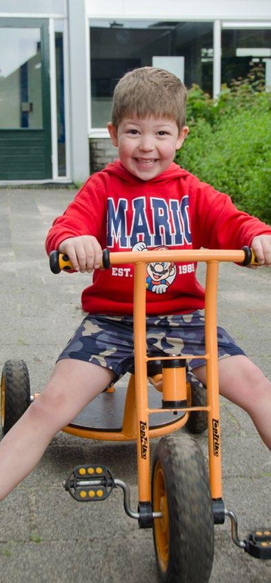 Een blije jongen rijdt op een grote driewieler op het schoolplein van Openbare Basisschool Kamperfoelie in Huizen. Een blije jongen rijdt op een grote driewieler op het schoolplein van Openbare Basisschool Kamperfoelie in Huizen.