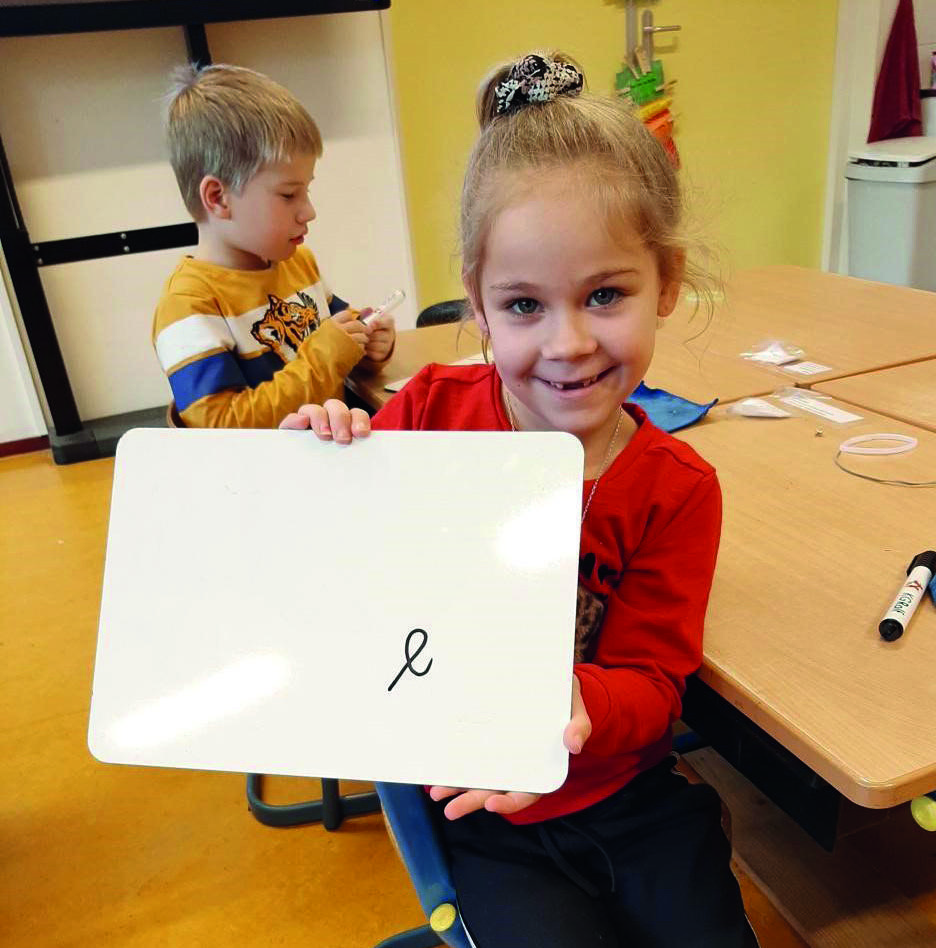 Een blije leerling van Kindcentrum het Rinket in Heemskerk toont haar schrijfoefening op een whiteboard. Een blije leerling van Kindcentrum het Rinket in Heemskerk toont haar schrijfoefening op een whiteboard.