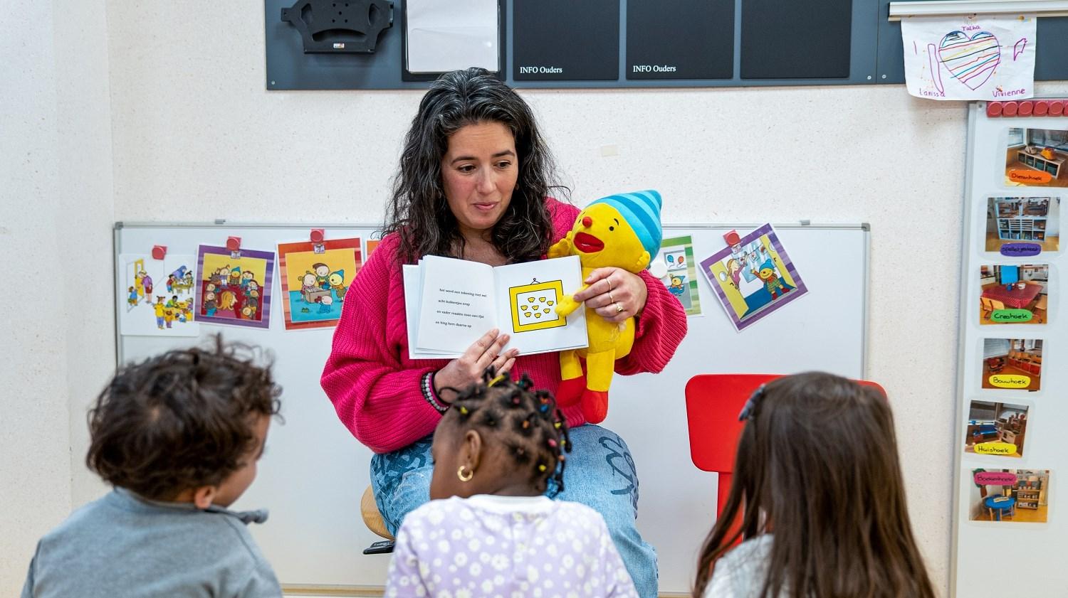 Een docente leest voor aan kinderen met een knuffel in de Ikra school in Dordrecht.