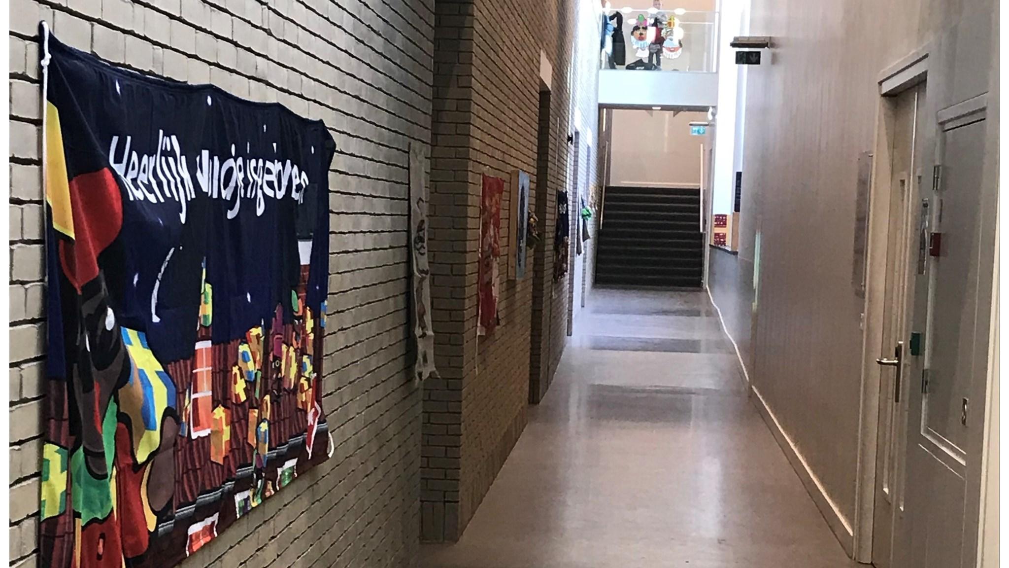 Een gang met een kleurrijk spandoek op de muur in Rk Bs De Mheyster in Hoensbroek. Een gang met een kleurrijk spandoek op de muur in Rk Bs De Mheyster in Hoensbroek.