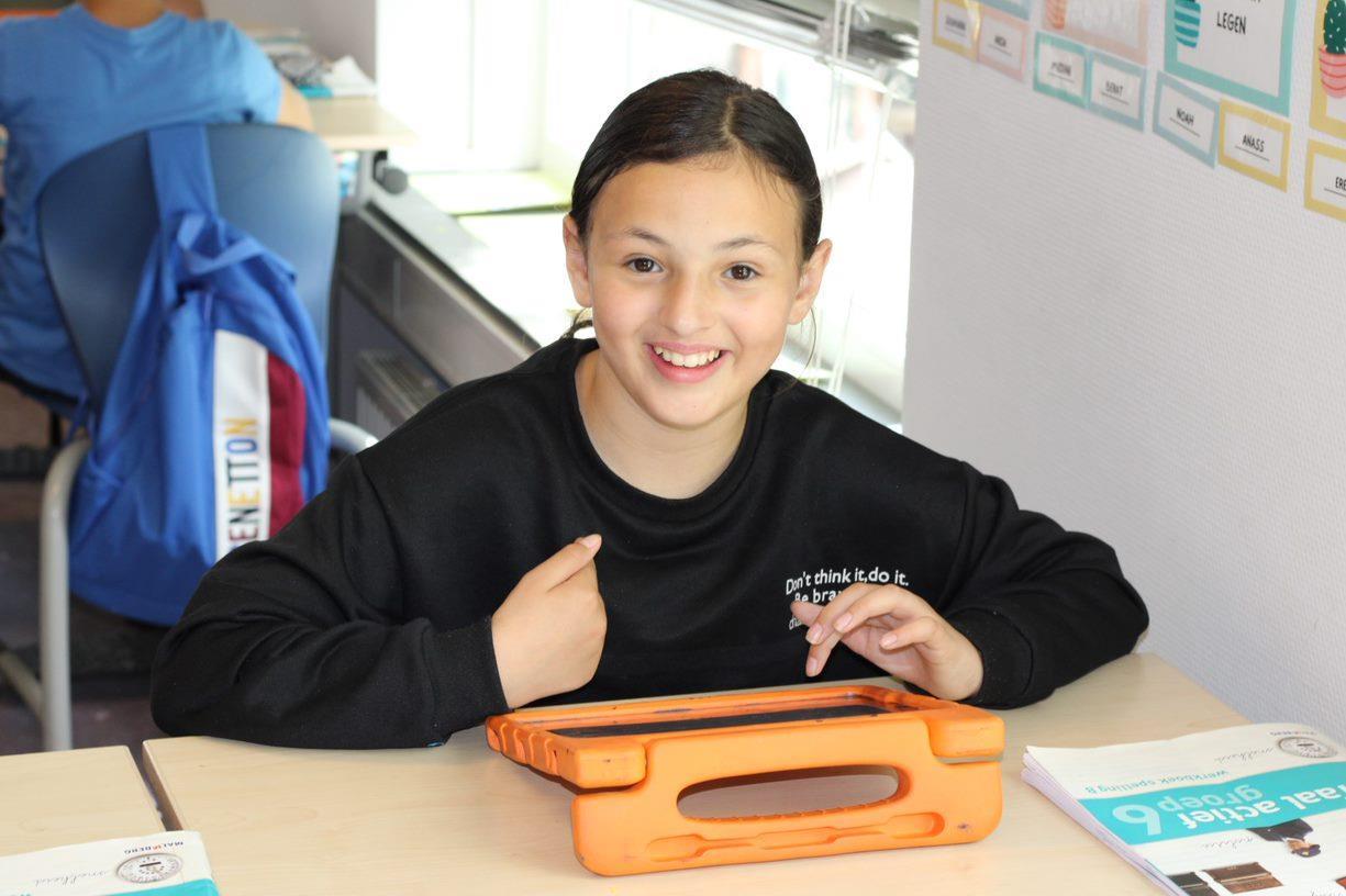 Een glimlachend kind aan een bureau met een tablet in de Prinses Marijkeschool in Den Haag. Een glimlachend kind aan een bureau met een tablet in de Prinses Marijkeschool in Den Haag.