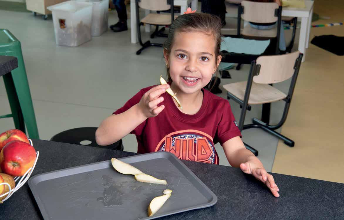 Een glimlachend meisje houdt een stuk fruit vast in de klas van Kindcentrum De Spreng in Hoevelaken. Een glimlachend meisje houdt een stuk fruit vast in de klas van Kindcentrum De Spreng in Hoevelaken.