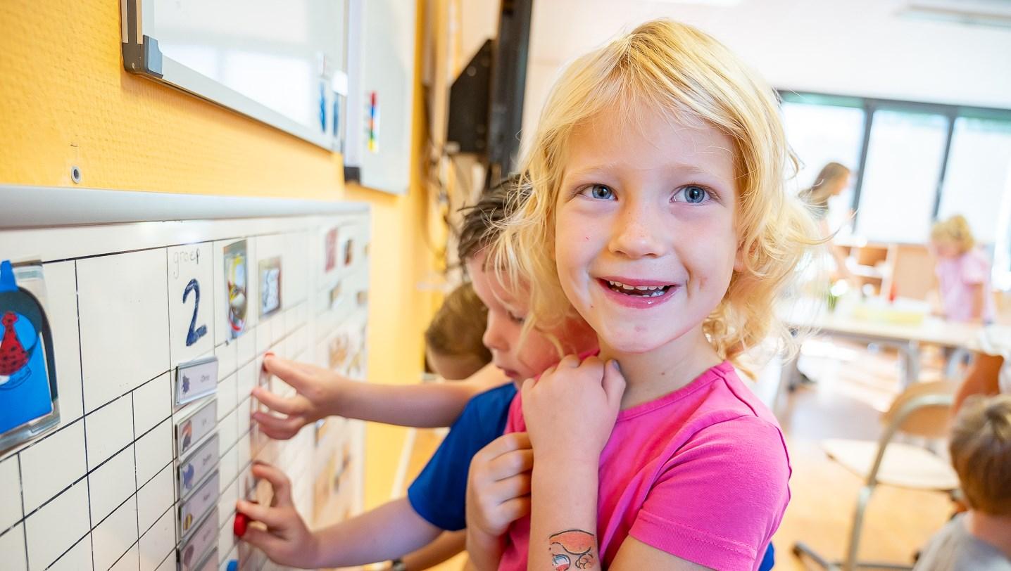 Een glimlachend meisje in een klasruimte van Daltonschool Willibrordus in Ruurlo terwijl ze leert. Een glimlachend meisje in een klasruimte van Daltonschool Willibrordus in Ruurlo terwijl ze leert.