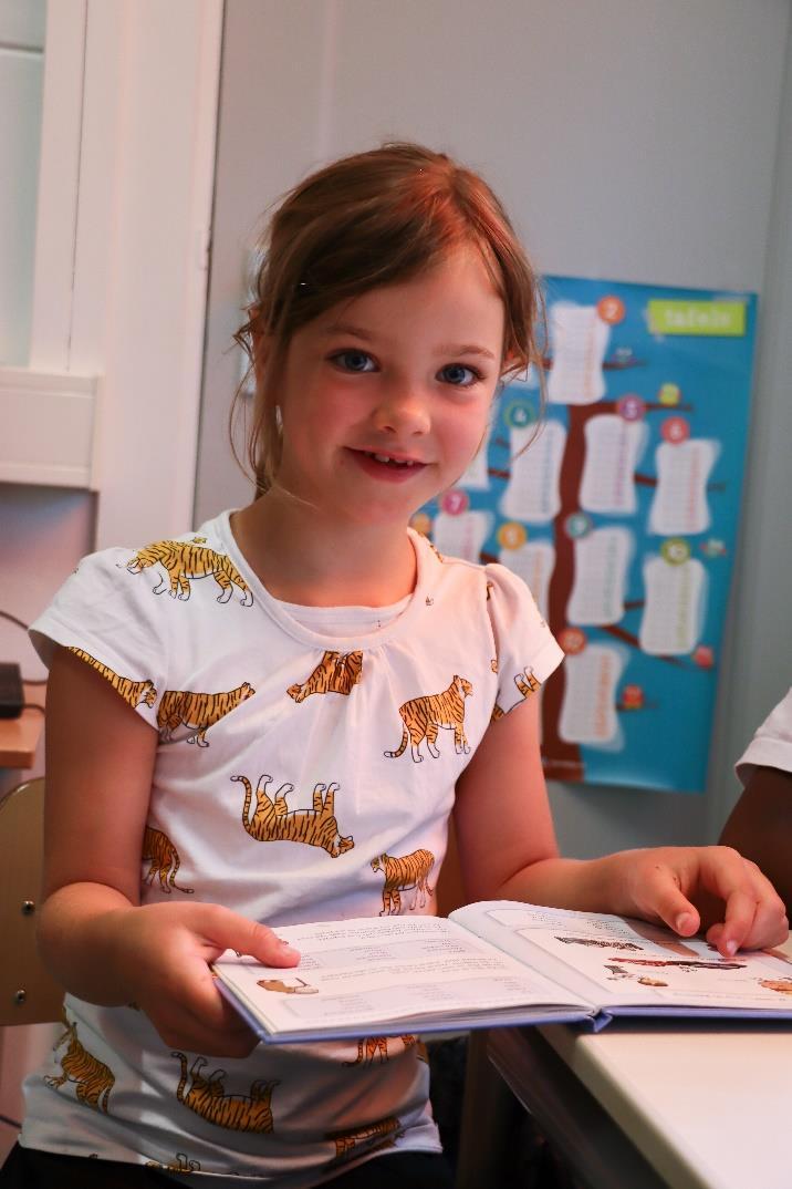 Een glimlachend meisje leest een boek in de klas van obs De Bosrand in Oostvoorne. Een glimlachend meisje leest een boek in de klas van obs De Bosrand in Oostvoorne.