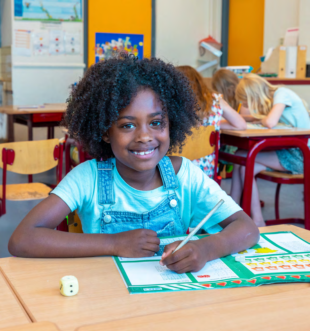 Een glimlachend meisje werkt aan een schoolopdracht in de klas van de Prins Mauritsschool in Delft. Een glimlachend meisje werkt aan een schoolopdracht in de klas van de Prins Mauritsschool in Delft.