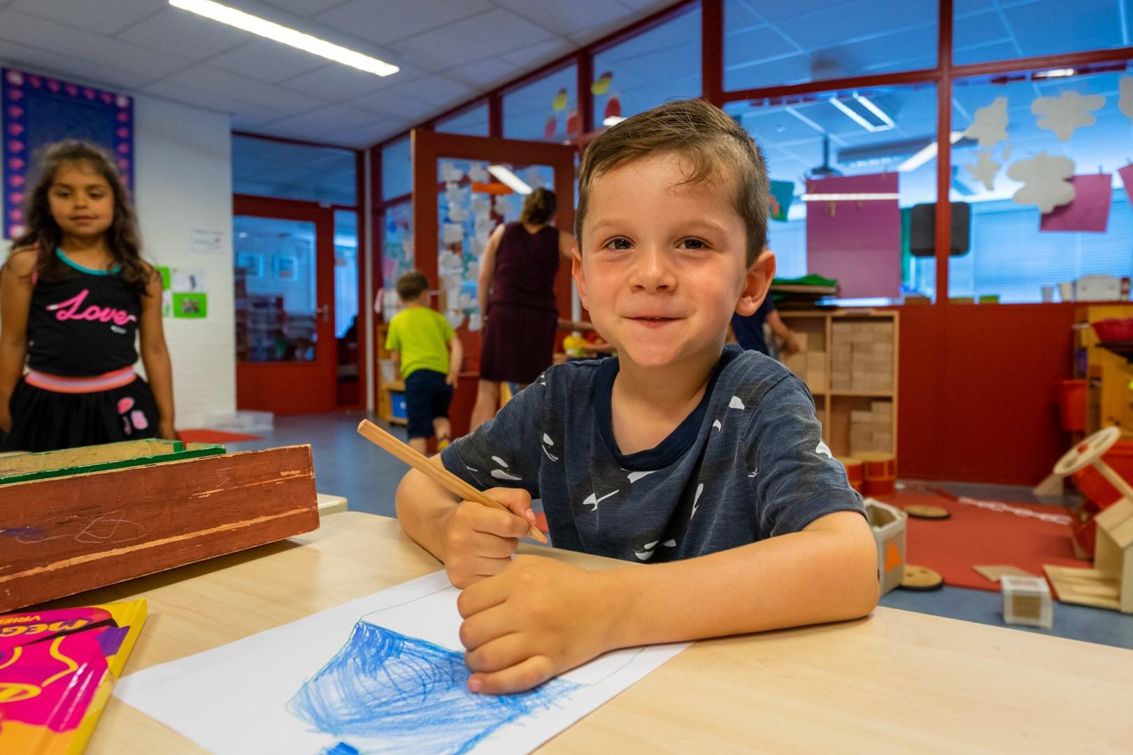 Een glimlachende jongen aan de Openbare Basisschool de Cocon in Alkmaar, terwijl hij enthousiast aan het tekenen is. Een glimlachende jongen aan de Openbare Basisschool de Cocon in Alkmaar, terwijl hij enthousiast aan het tekenen is.
