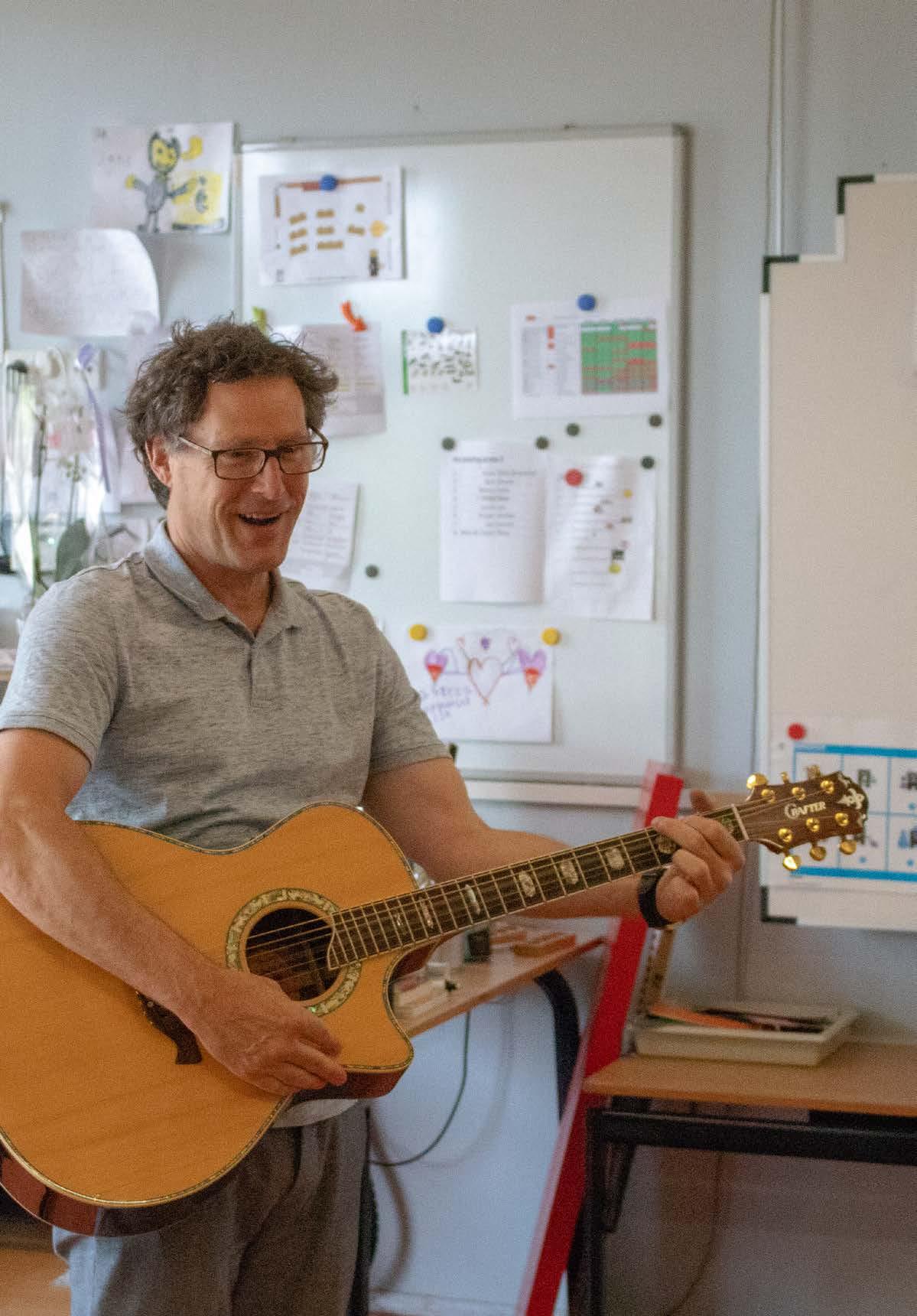 Een glimlachende leraar met een gitaar in de klas van Openbare basischool De Zeevonk in Zandvoort. Een glimlachende leraar met een gitaar in de klas van Openbare basischool De Zeevonk in Zandvoort.