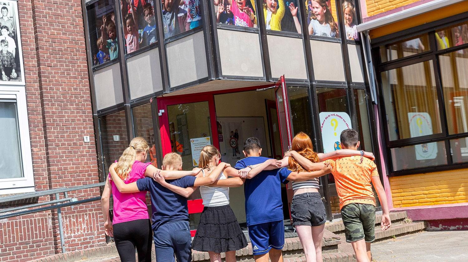 Een groep kinderen loopt hand in hand naar de ingang van Openbaar Basisschool Weisterbeek in Horst. Een groep kinderen loopt hand in hand naar de ingang van Openbaar Basisschool Weisterbeek in Horst.