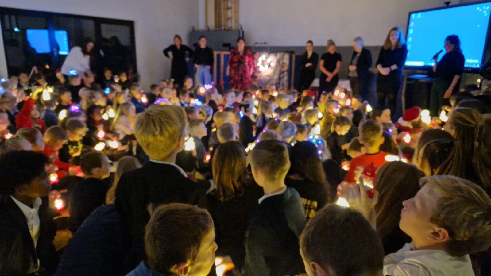 Een groep kinderen met lichtjes verzameld in O.B.S. De Punter in Giethoorn tijdens een speciale gebeurtenis.