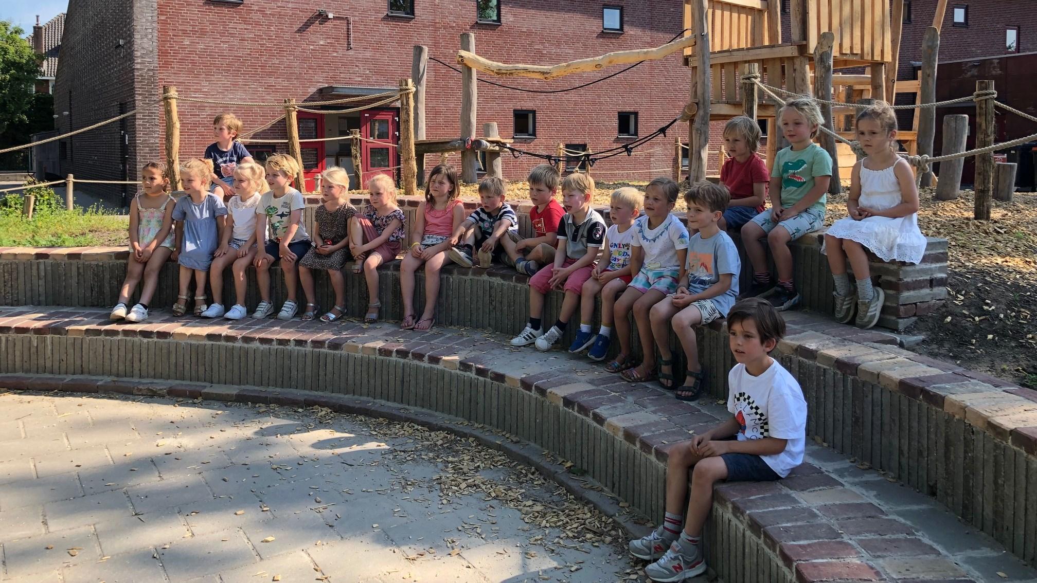 Een groep kinderen zit samen op het schoolplein van de Godelindeschool in Naarden. Een groep kinderen zit samen op het schoolplein van de Godelindeschool in Naarden.