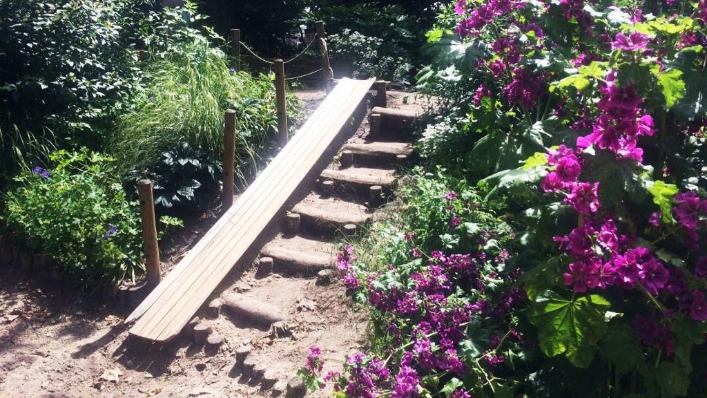 Een houten bruggetje leidt over de trappen in de bloeiende tuin van de Rudolf Steiner School Krimpen in Krimpen aan den IJssel. Een houten bruggetje leidt over de trappen in de bloeiende tuin van de Rudolf Steiner School Krimpen in Krimpen aan den IJssel.