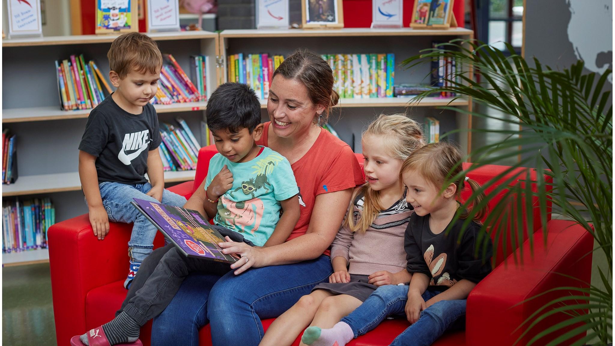 Een jonge lerares leest een boek voor aan een groep kinderen op KBS Stepping Stones in Utrecht. Een jonge lerares leest een boek voor aan een groep kinderen op KBS Stepping Stones in Utrecht.