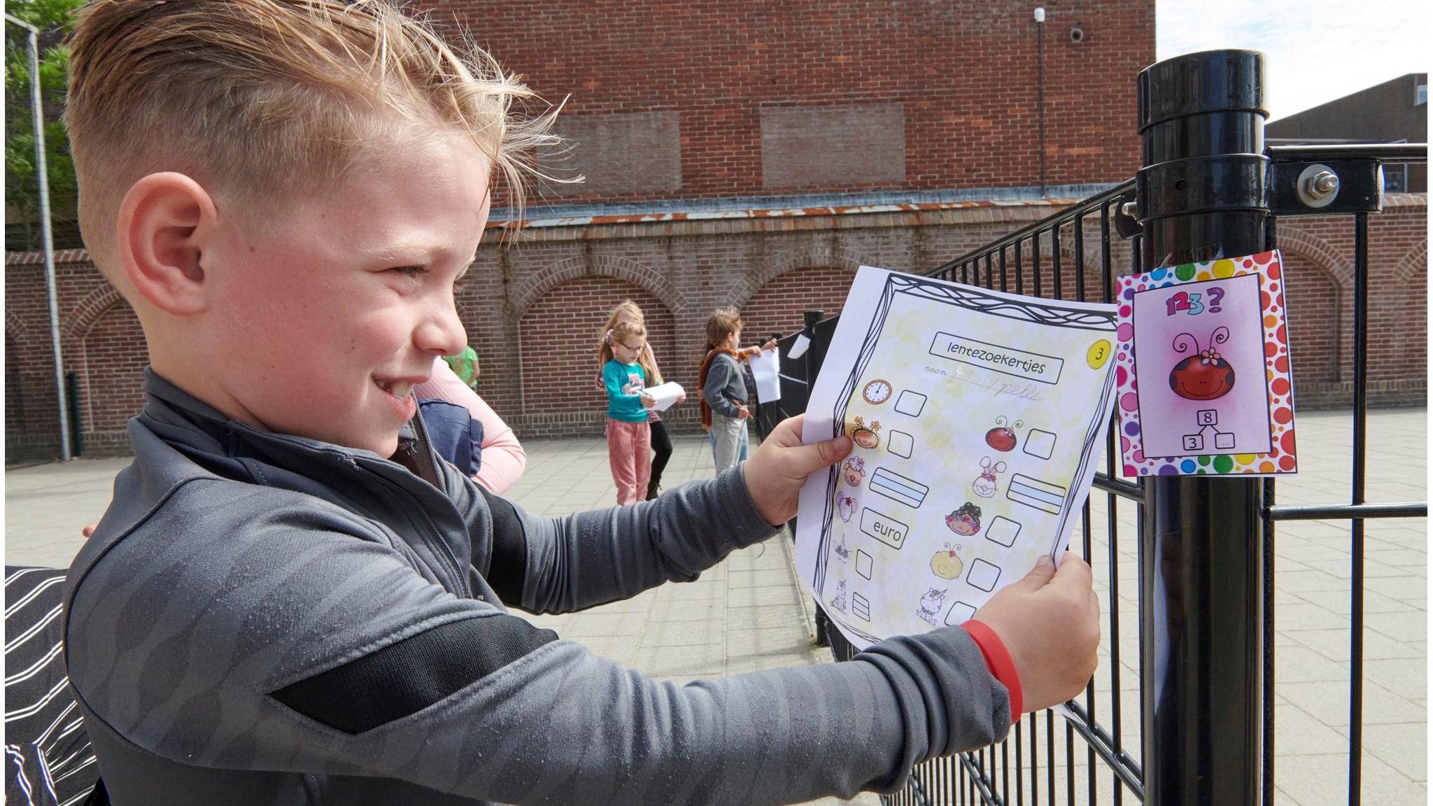 Een jongen bekijkt een lentezoekkaart op het schoolplein van de Cruquiusschool in Haarlem. Een jongen bekijkt een lentezoekkaart op het schoolplein van de Cruquiusschool in Haarlem.