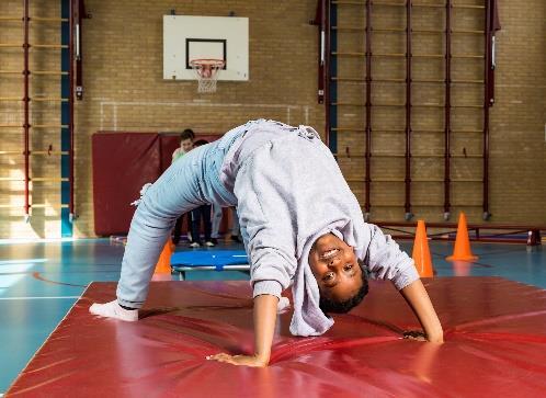 Een jongen die een acrobatische houding aanneemt in de gymzaal van Basisschool De Botteloef in Amsterdam. Een jongen die een acrobatische houding aanneemt in de gymzaal van Basisschool De Botteloef in Amsterdam.