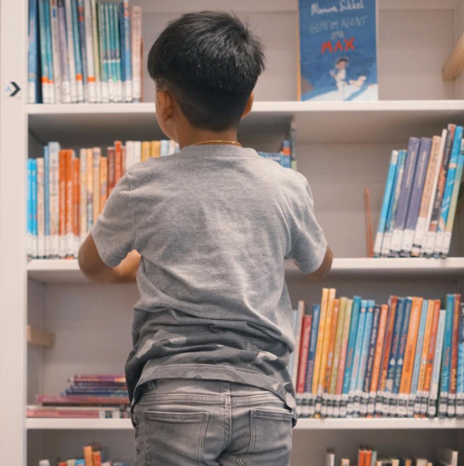 Een jongen in 'De Barkentijn' in Rotterdam haalt boeken van de plank in de bibliotheek. Een jongen in 'De Barkentijn' in Rotterdam haalt boeken van de plank in de bibliotheek.